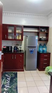 a kitchen with wooden cabinets and a stainless steel refrigerator at Palm Comfort Apartment in Bamburi