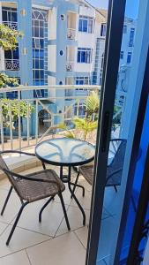 a patio with a table and chairs on a balcony at Palm Comfort Apartment in Bamburi