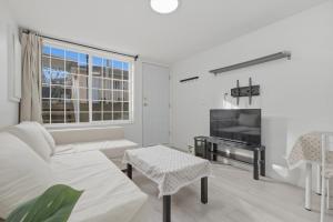 a white living room with a couch and a tv at Central Van 1bedroom Suite in Vancouver