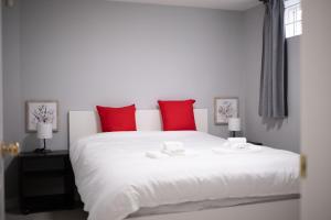a bedroom with a large white bed with red pillows at Central Van 1bedroom Suite in Vancouver