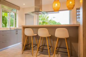 a kitchen with three stools at a kitchen counter at ELYMUS - Spacious 3-Bedroom Apartment With Private Rooftop and Balcony - Near Le Morne And Lagoon in La Gaulette