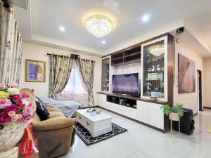a living room with a couch and a tv at Baan Khun Pim Pool Villa in Ban Suan Maphrao
