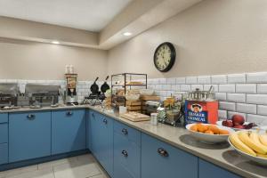 una cocina con armarios azules y un reloj en la pared en Country Inn & Suites by Radisson, Ankeny, IA, en Ankeny