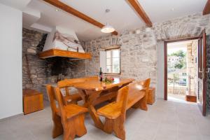 a dining room with a wooden table and benches at Stone House Villa Darinka in Vela Luka