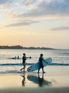 two people walking on the beach with their surfboards at Secret Gem in Arugam Bay