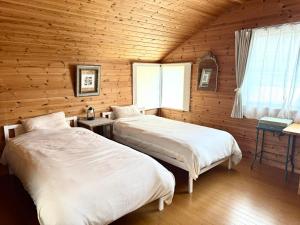 two beds in a room with wooden walls at chez Petit Lapinシェプチラパン in Karuizawa