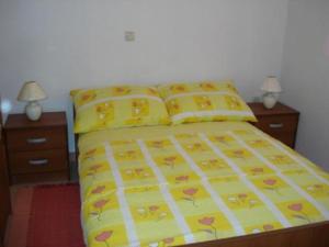 a bedroom with a bed with yellow sheets and pillows at Apartments Eden in Jadranovo