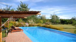 a swimming pool in a garden with a pergola at El Caserio Casas de Campo in Villa Cura Brochero