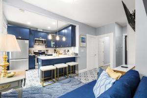 a living room with a blue couch and a kitchen at Bright 2BR Retreat Walk to PATH NYC Access in Jersey City