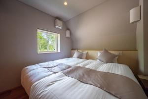 a bedroom with a large white bed with a window at ERUSA Rusutsu in Rusutsu
