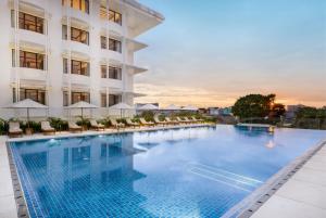 a hotel swimming pool with chairs and umbrellas at Grand Hotel De Djokja in Yogyakarta