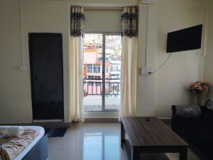 a living room with a couch and a table and a window at Fanai Inn in Āīzawl