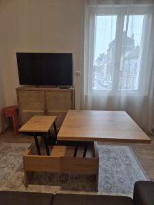 a living room with a table and a flat screen tv at le st fursy 1 in Péronne