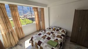 a bedroom with a bed and a large window at Amazing views PISAQ in Pisac
