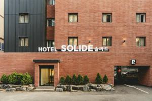 a red brick hotel building with a hotel soluble sign on it at Hotel Solide Cheonan in Cheonan