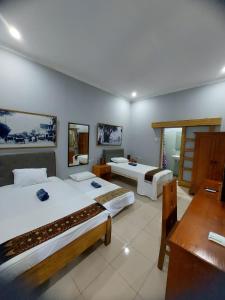 a room with two beds and a table and a desk at Hamemayu Homestay in Jejeran