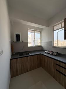 a kitchen with wooden cabinets and a sink and two windows at Live Easy in Mātigara