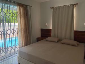a bedroom with a bed and a window with a pool at Solmera Villa in Grand-Baie
