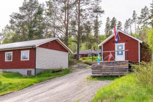 a red house and a building on a dirt road at Lagom huset in Årjäng