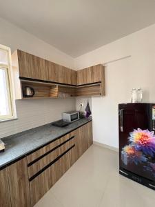 a kitchen with a black refrigerator and wooden cabinets at Live Easy in Mātigara