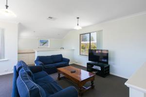 a living room with two blue couches and a tv at Seahaven by Rockingham Apartments in Rockingham