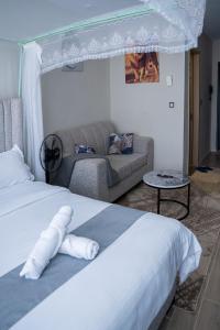 a bedroom with a white bed and a couch at Taurus B8-6 in Nairobi