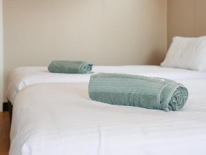 two beds with white sheets and a green towel on them at Parkes Cabins in Parkes