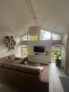 a living room with a couch and a flat screen tv at Slechtvalk 7 in Hulshorst