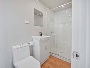 a white bathroom with a toilet and a shower at Parkes Cabins in Parkes