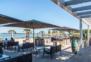 a patio with tables and umbrellas on the beach at Slechtvalk 7 in Hulshorst