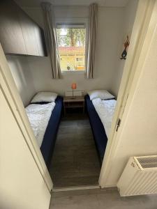 two beds in a small room with a window at Slechtvalk 7 in Hulshorst +16 photos