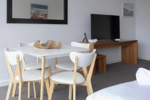 a room with a table and chairs and a television at Bay View - The Trio in Lorne