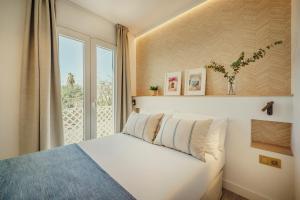 a bedroom with a white bed and a window at Beneste Nerja Hostal in Nerja