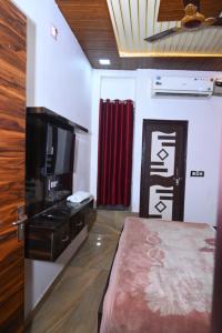 a room with a bed and a television and a red curtain at Hotel Royal Vista in Meerut