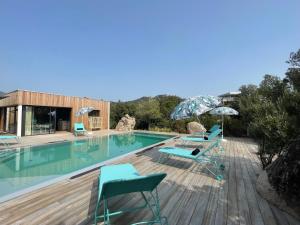 a swimming pool with chairs and umbrellas on a deck at luxe et sérénité in Lecci