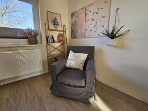 a chair with a pillow in a room with a window at Küstenglück 2 Stylisches Apartment mit Meerblick - 200m zum Strand & Bäcker in Dahme