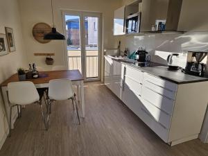 a kitchen with white cabinets and a table and chairs at Küstenglück 2 Stylisches Apartment mit Meerblick - 200m zum Strand & Bäcker in Dahme