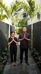 a man and a woman standing in front of a fence praying at Prana Ubud in Tegalalang
