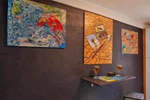 a wall with paintings and two wine glasses on it at Casa Erbalunga Au cœur du village proche du port et de la plage in Erbalunga