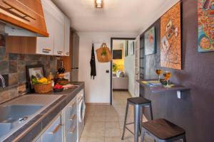 a kitchen with a sink and a counter with two stools at Casa Erbalunga Au cœur du village proche du port et de la plage in Erbalunga