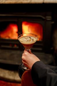 a person holding a drink in front of a fireplace at Camps Bay Retreat Hotel in Cape Town