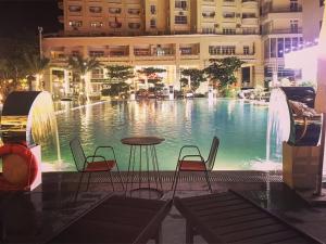 a large pool with chairs and a table in front of a building at TA Nhatrang Apartment in Nha Trang