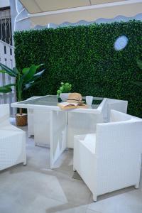 a white table and chairs and a green hedge at Coastline 1 in Perea