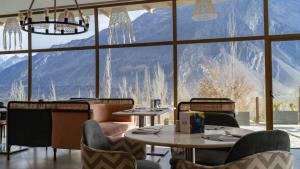 a restaurant with tables and chairs and a large window at Ambiance Resort Hunza in Hunza Valley
