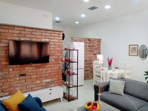 a living room with a brick wall with a tv at Sava & Double Rooms in Prijedor