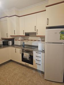 a kitchen with white cabinets and a refrigerator at apartamento castelao in Cedeira