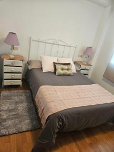 a bedroom with a large bed with two night stands and two lamps at apartamento castelao in Cedeira