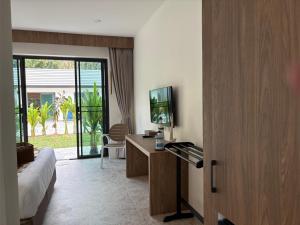 a hotel room with a bed and a tv and a desk at Tiger on the Beach in Krabi