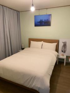a bedroom with a large bed with white sheets at 산초리니 Sanchorini in Busan