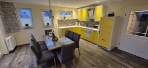a kitchen with yellow cabinets and a table and chairs at Ferienhaus Lachmöwe in Fehmarn +18 photos
